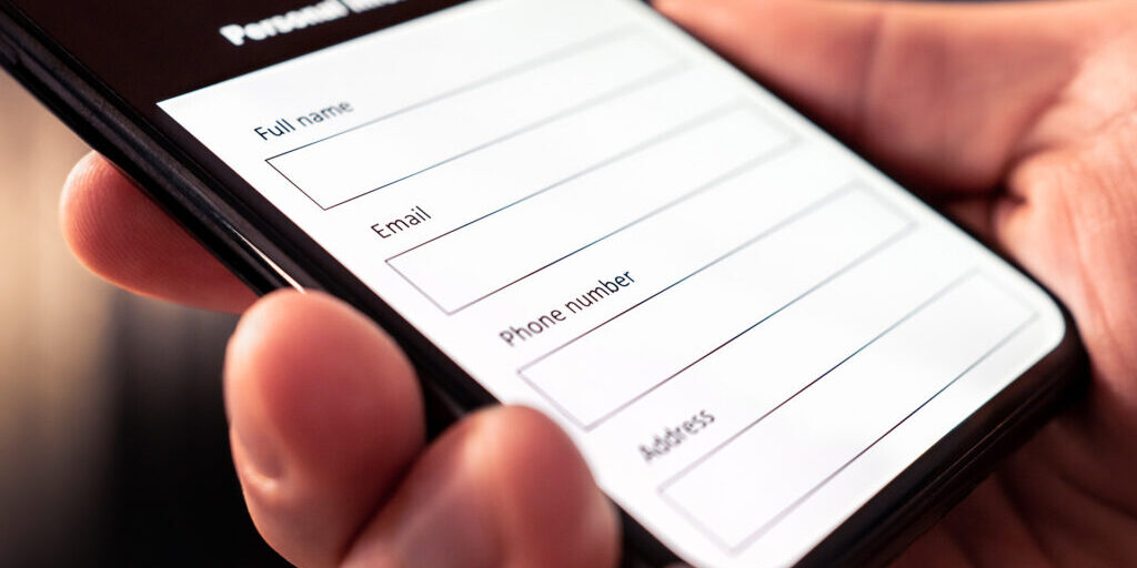 Hand holding a mobile device with a contact form displayed on the screen