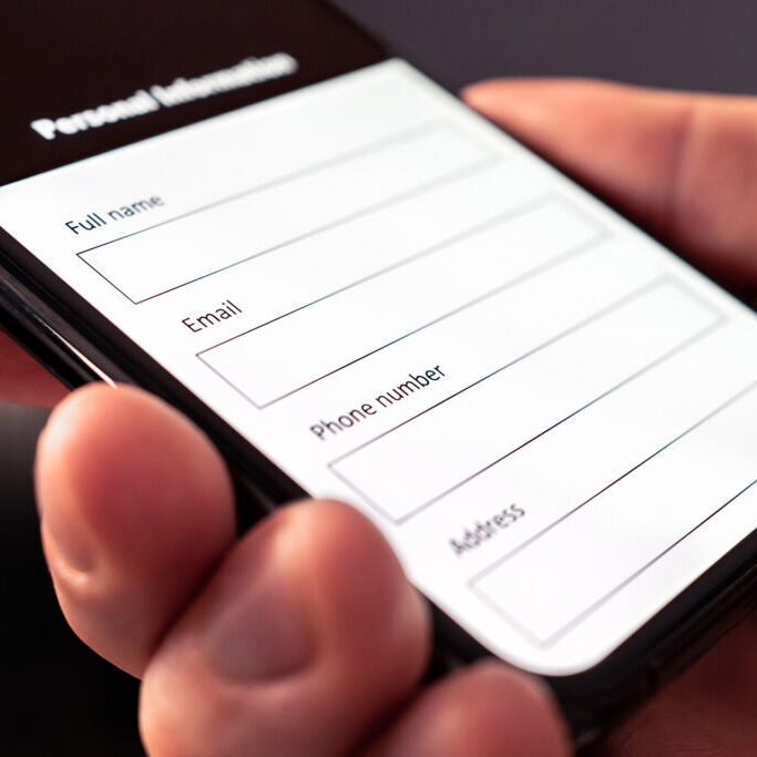 Hand holding a mobile device with a contact form displayed on the screen