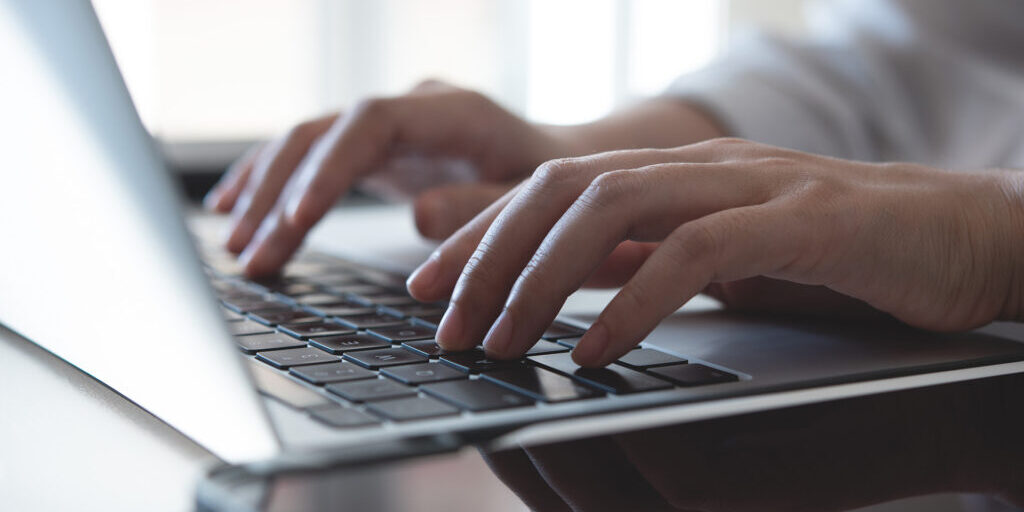 Person's fingers typing on laptop keyboard
