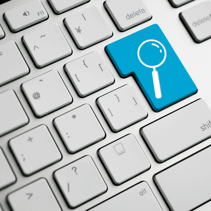 Close-up of a white computer keyboard with a unique blue key featuring a magnifying glass icon, symbolizing a search function.